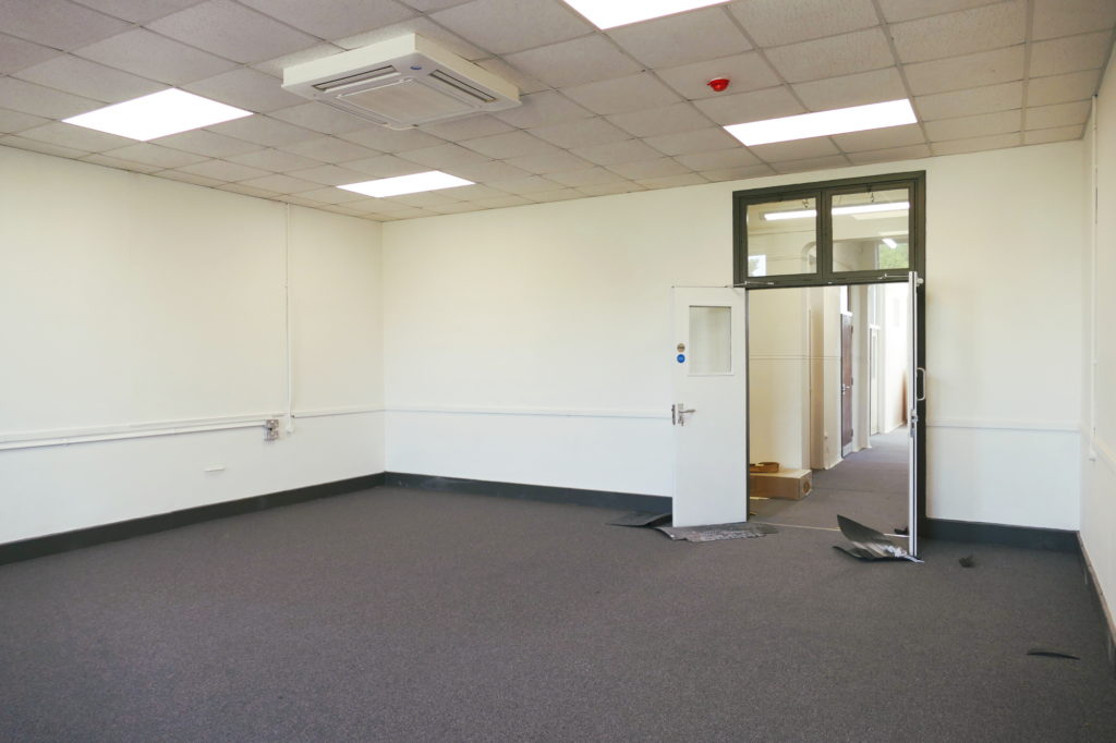 Interior of light modern office with door leading to corridor