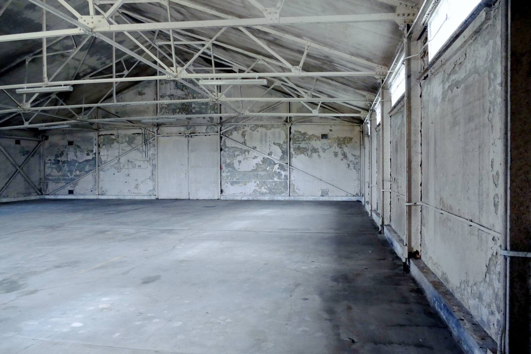 Interior of old industrial warehouse with white walls and concrete floor