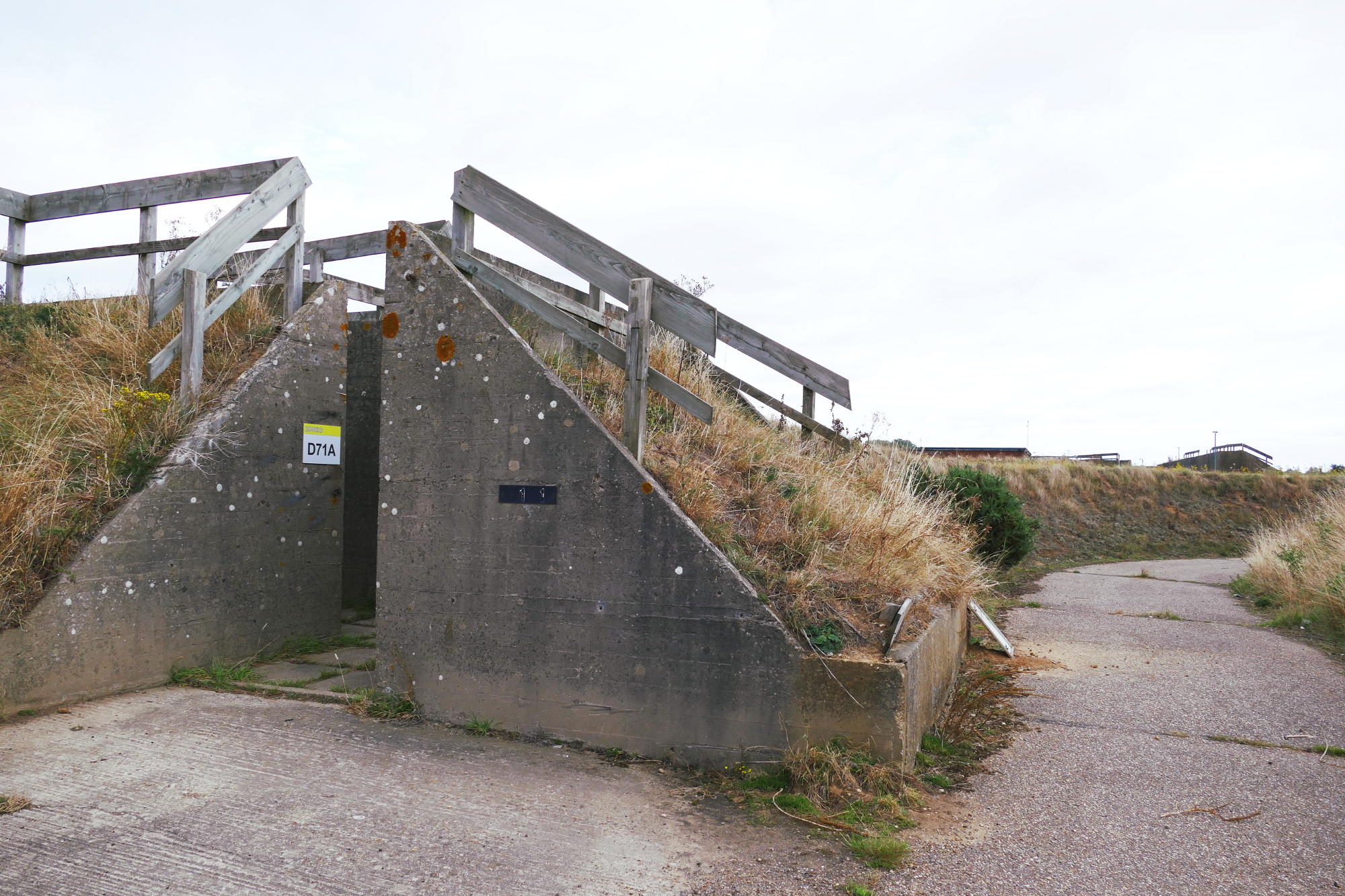 Exterior of old RAF industrial storage unit with concrete walls, concrete road and grass