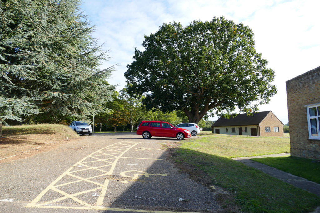 Concrete car park with disabled spaces and greenery in background